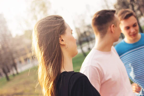 Young beautiful long hair girl on two boys friends background in city street — Stock Photo, Image