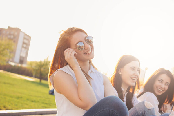 Group of young happy girls friends enjoy life on summer city street, sunset background