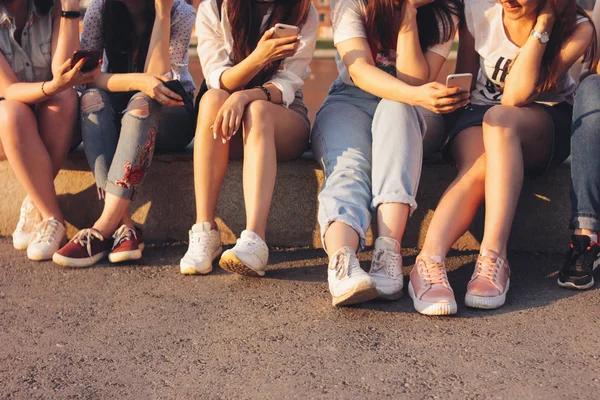 Foto de corte de grupo de jovens meninas bronzeadas felizes amigos reais usando móvel no fundo do pôr do sol — Fotografia de Stock