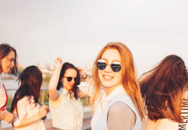 Positivo bela menina ruiva feliz nos óculos de sol espelho com amigos no fundo do céu azul, verão hora do pôr-do-sol — Fotografia de Stock