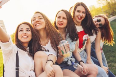 Yaz şehir caddesinde selfie yapan genç mutlu kaygısız kız arkadaşlar grubu, gün batımı zamanı arka plan