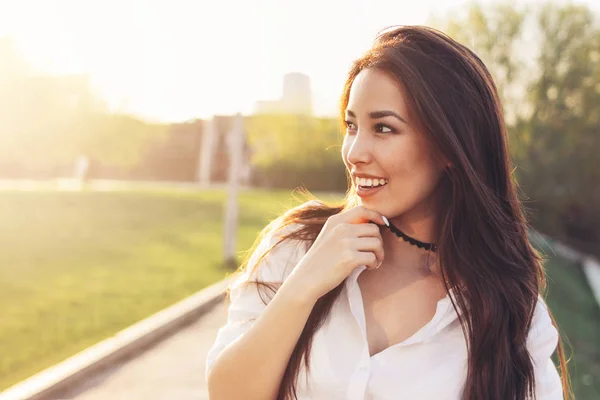Pozitivní krásná, šťastná Asijská dívka v bílé košili na pozadí města, letní čas západu slunce — Stock fotografie