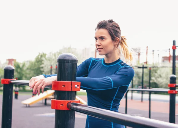 Atractiva mujer en forma joven en el descanso de ropa deportiva en el área de entrenamiento de la calle. El estilo de vida saludable en la ciudad — Foto de Stock