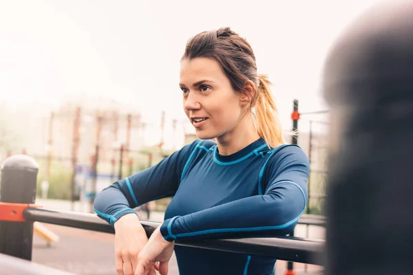 Atractiva mujer en forma joven en el descanso de ropa deportiva en el área de entrenamiento de la calle. El estilo de vida saludable en la ciudad — Foto de Stock