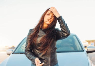 Güzel büyüleyici esmer uzun saçlı genç asyalı kadın arabasının yanında siyah deri ceket