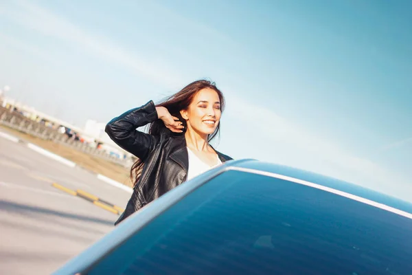 Happpy mooie charmante brunette lang haar jonge Aziatische vrouw in zwart lederen jas in de buurt van haar auto — Stockfoto