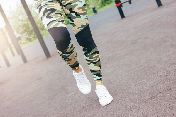 身着军装的年轻女子穿着在街头锻炼区跑步的作物照片。城市健康的生活方式 — 图库照片