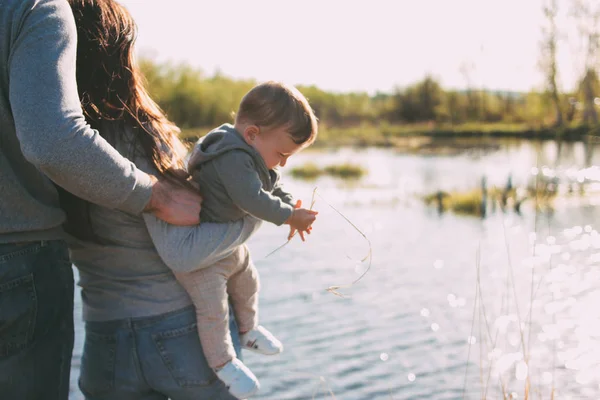Lycklig familj med söt baby pojke på sjön vatten bakgrund utomhus, känslighet för natur koncept — Stockfoto