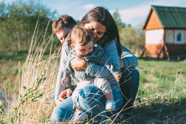 Lycklig familj med söt baby pojke på byhus och natur bakgrund utomhus, känslighet för natur koncept — Stockfoto