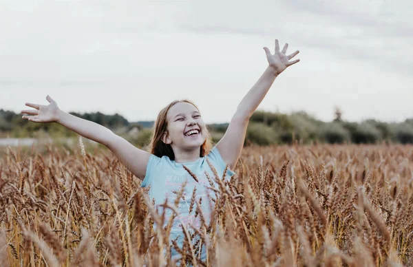 Feliz linda tweens menina com cabelos longos no campo de trigo ao pôr do sol — Fotografia de Stock