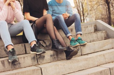 Arkadaş Millennials öğrenci gençler şehir sokakta oturan grup Kırpma fotoğraf, dostluk, ayaklar üzerinde odak kadar yakın 