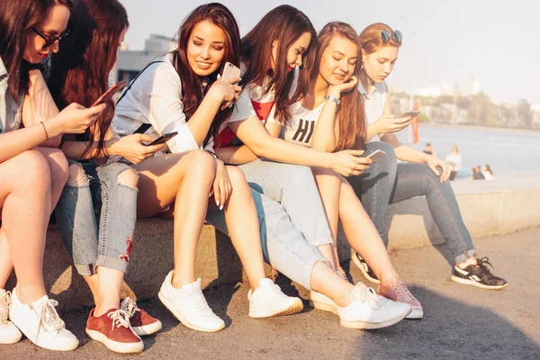 Grupo de jovens meninas felizes amigos reais estudantes usando móvel na rua da cidade no pôr do sol fundo — Fotografia de Stock