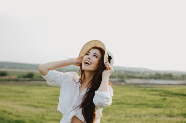 Beyaz giysiler ve saman şapka güzel mutlu kaygısız uzun saçlı Asya kız günbatımı doğa alanında yaşam sahiptir. Doğa konseptine duyarlılık