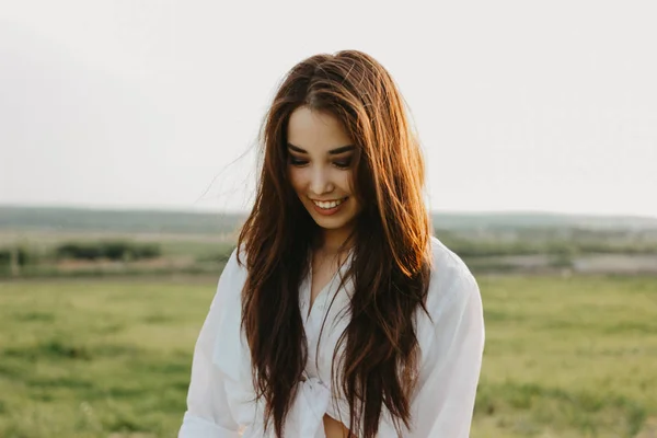 Портрет красивой беззаботной длинношерстной девушки в белой одежде на поле на закате. Чувствительность к природе — стоковое фото