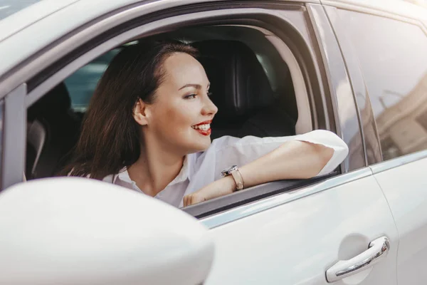 Mooie succesvolle elegante glimlachende brunette jonge vrouw met rode lippen het rijden van de personenauto — Stockfoto