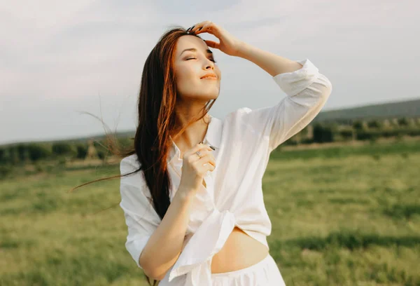 Retrato de bela menina cabelo longo despreocupado em roupas brancas no campo ao pôr do sol. Sensibilidade ao conceito de natureza — Fotografia de Stock