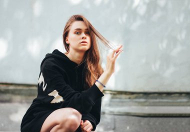 Duvar arka planda siyah kapüşonlu genç güzel uzun saç mutsuz kız moda modeli hipster Samimi portre