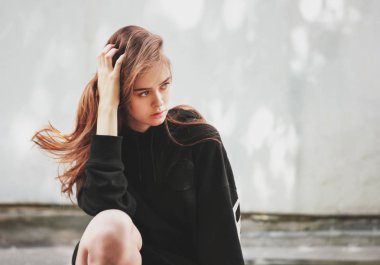 Duvar arka planda siyah kapüşonlu genç güzel uzun saçlı kız model hipster Samimi portre