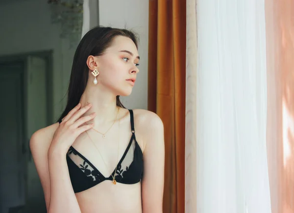 Sensual jovem bonito modelo de moda menina de cabelo longo em roupa interior e Jewerly accessorise perto da janela no quarto — Fotografia de Stock