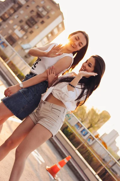 Duas belas namoradas despreocupadas se divertir no estacionamento no fundo da cidade por do sol da noite, hora de verão — Fotografia de Stock