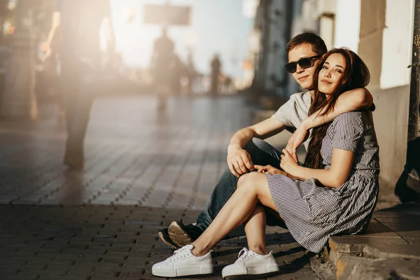 Felice giovane coppia innamorata adolescenti amici vestiti in stile casual seduti insieme sulla strada della città — Foto Stock