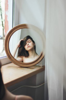 Yuvarlak ayna önünde Şehvetli genç güzel uzun saç kız model, yumuşak odak, yüksek iso