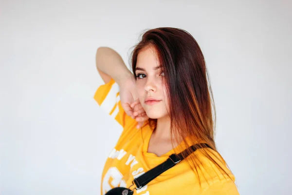 Gri arka plan üzerinde sarı t-shirt koyu uzun saçlı tipical düşünceli genç kız Portresi — Stok fotoğraf