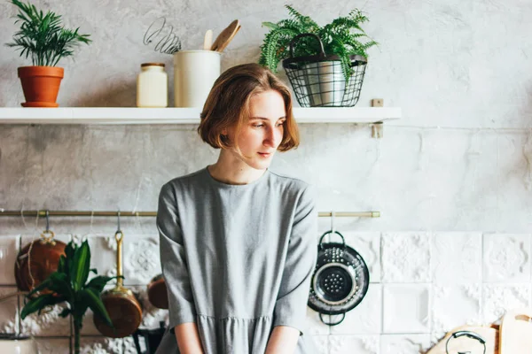 Jovem mulher em vestido cinza na cozinha, interior escandinavo, vida lenta — Fotografia de Stock
