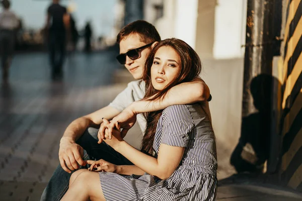 Feliz jovem casal apaixonado adolescentes amigos vestidos em estilo casual sentados juntos na rua da cidade — Fotografia de Stock
