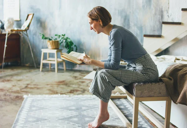 Junge Frau liest Buch auf der Treppe im Loft Kunstwerk Atelierraum, langsames Leben — Stockfoto
