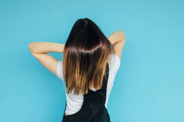 Mavi arka plan üzerinde izole arkasından beyaz t-shirt parlak koyu uzun saçlı kız