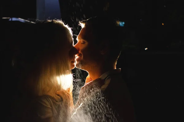 Jovem casal feliz no amor beijando à noite sob chuva. Foto com efeitos de flash — Fotografia de Stock
