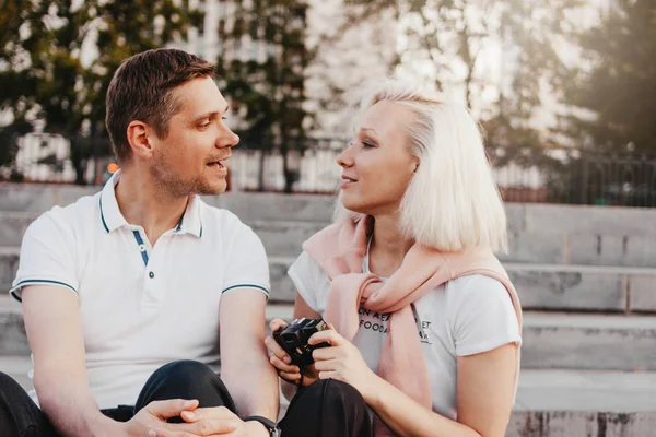 Joven feliz pareja en el amor dispara entre sí en la cámara retro en la calle de la ciudad — Foto de Stock