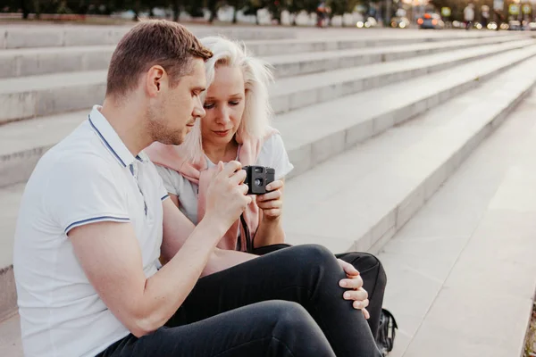 Joven feliz pareja en el amor dispara entre sí en la cámara retro en la calle de la ciudad — Foto de Stock