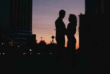 Gün batımında şehir sokakta öpüşme aşk genç mutlu çift silüeti 