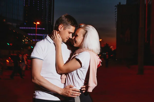 Joven pareja feliz enamorada besándose en la calle de la ciudad nocturna. Foto con efectos flash — Foto de Stock