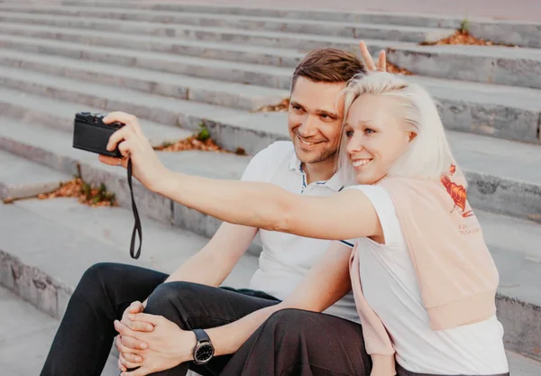 Joven feliz pareja en el amor haciendo selfie en la cámara retro en la calle de la ciudad — Foto de Stock