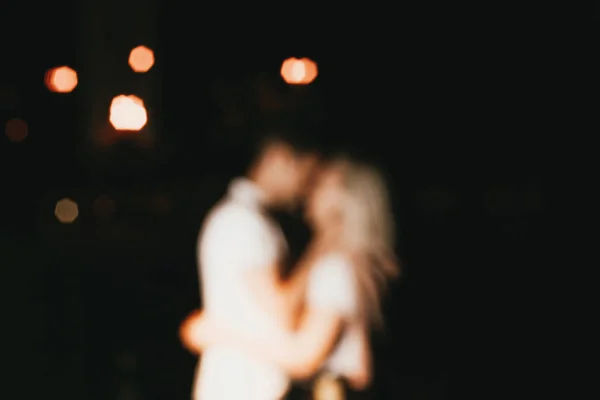 Young happy couple in love kissing in night. Blurred background — Stock Photo, Image