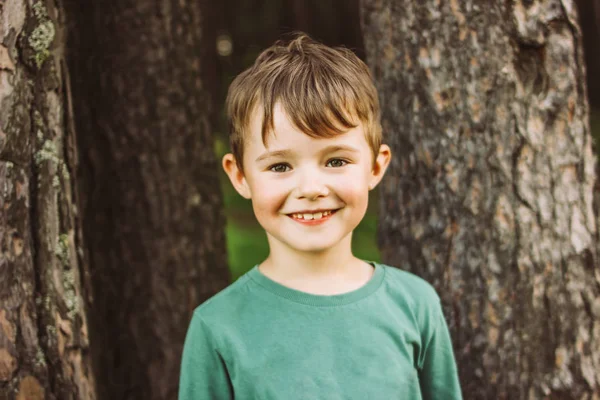 Portrait d'un garçon charmant avec un large sourire sur le fond de pins dans la forêt — Photo