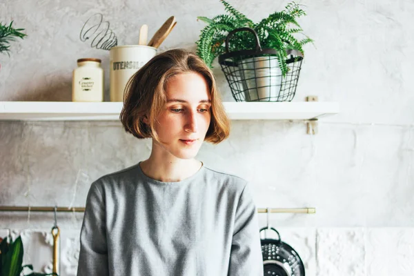 Jovem mulher em vestido cinza na cozinha, interior escandinavo, vida lenta — Fotografia de Stock