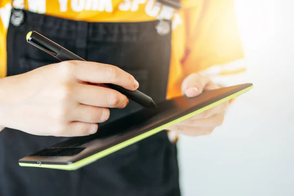 Sarı tişörtlü genç kadının elinde kalemli grafik tablet, gri arka plan üzerinde izole