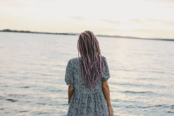 Hermosa joven romántica con trenzas africanas en vestido en la playa, vista desde atrás, tiempo de vacaciones de verano —  Fotos de Stock