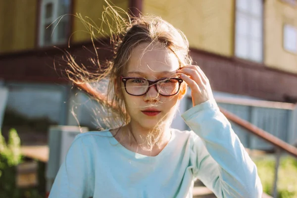 Close up retrato de encantadora menina sorridente em óculos de fundo velho casa de campo de madeira, tempo de verão no lado do país — Fotografia de Stock