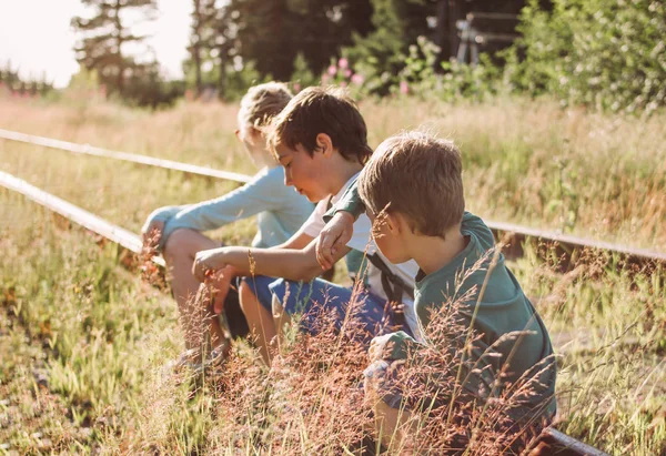 Группа детей-подростков на железной дороге на закате, летнее время в сельской местности — стоковое фото