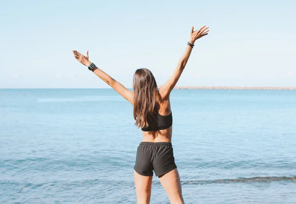 Jeune mince athlétique cheveux longs femme heureuse en vêtements de sport faire des exercices sur la plage de la mer le matin, mode de vie sain — Photo