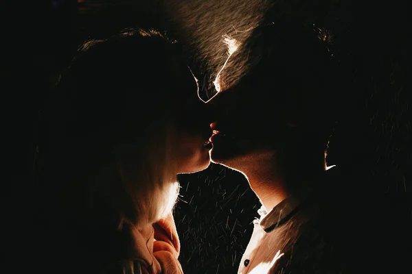 Yağmur altında gece öpüşme aşk genç mutlu çift silüeti. Flaş efektleri ile fotoğraf