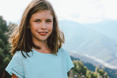 Gülümseyen ara kız güzel dağların arka planda kameraya bakarak, aile seyahatkonsepti macera yaşam tarzı