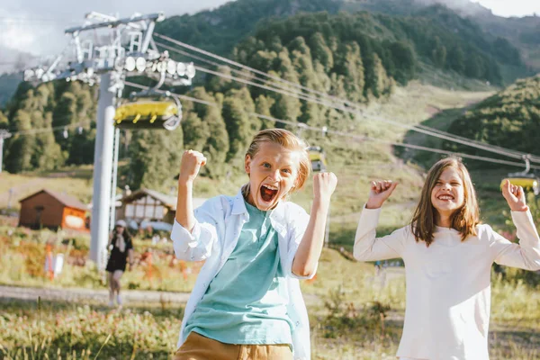 Niños felices hermanos y hermanas amigos contra el fondo del resort de montaña, concepto de aventura de viaje en familia — Foto de Stock