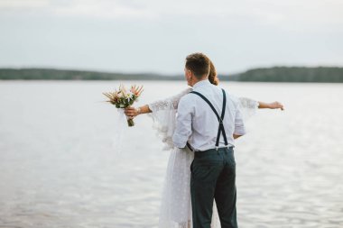 Göl yakınında Mutlu yeni evli çift, boho buketi ile gelin esmer genç kadın, portre açık kapatın