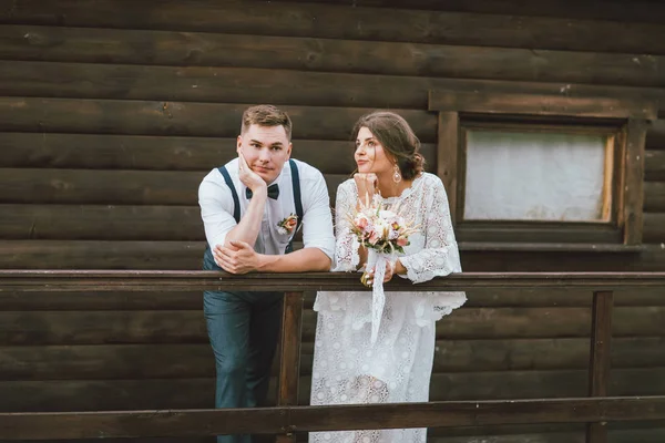 Забавная новобрачная пара, улыбающаяся брюнетка невесты молодая женщина с букетом в стиле бохо с женихом — стоковое фото